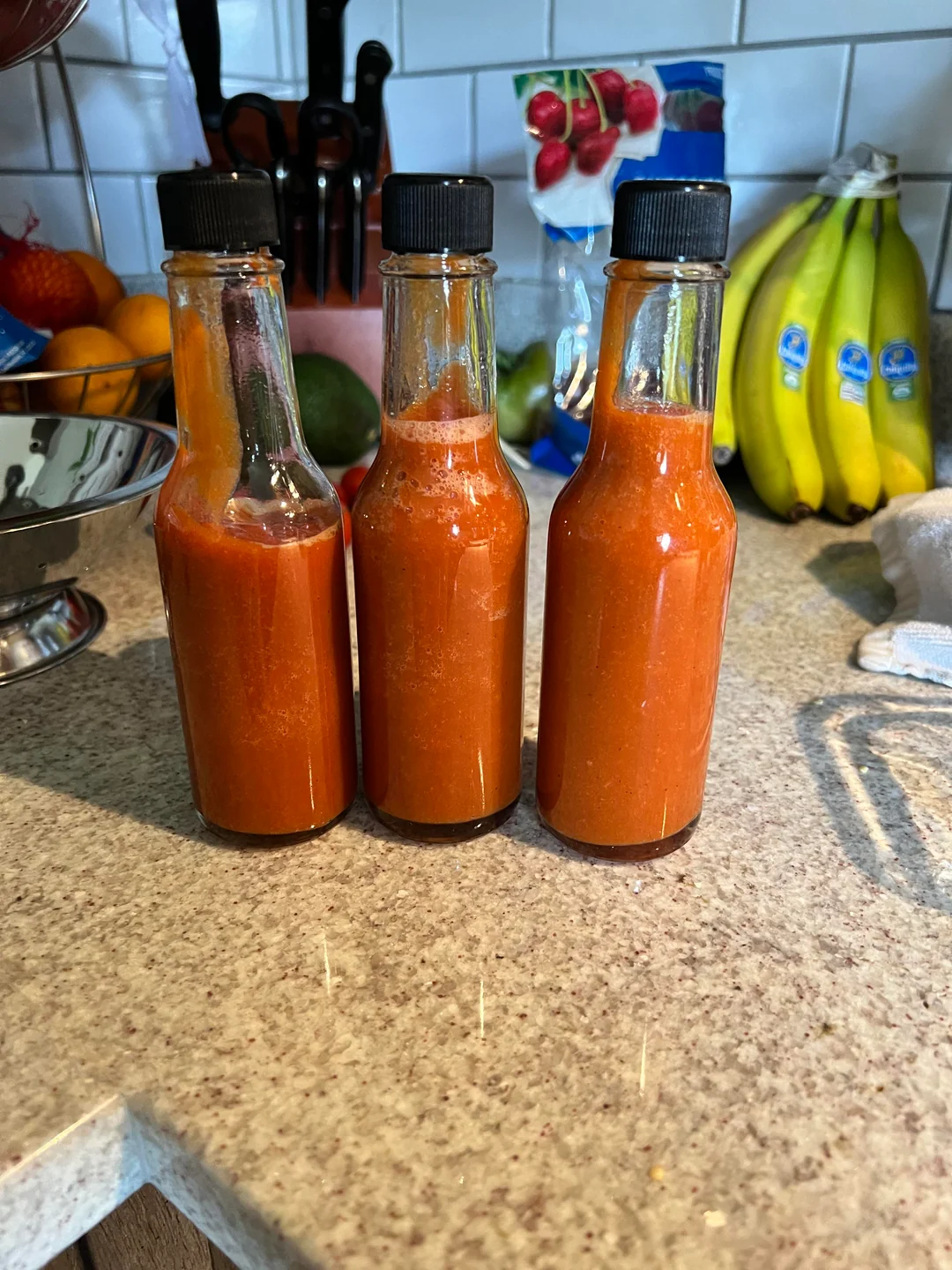 The finished hot sauce next to the bottles I reuse